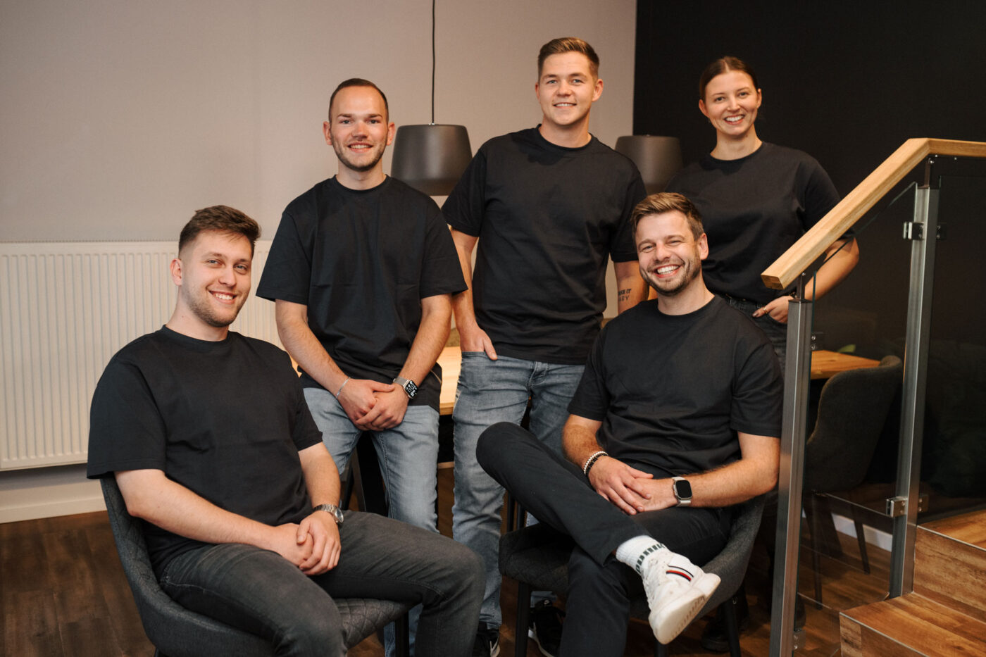 Fünf Teammitglieder von Möhle Maschinenbau posieren lächelnd gemeinsam in einem modernen Büro, alle in schwarzen T-Shirts.