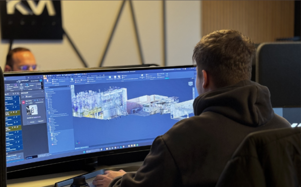 Ein Mann arbeitet an einem ultrabreiten Monitor mit einer 3D-CAD-Software, auf dem ein digitaler Gebäudescanner sichtbar ist.