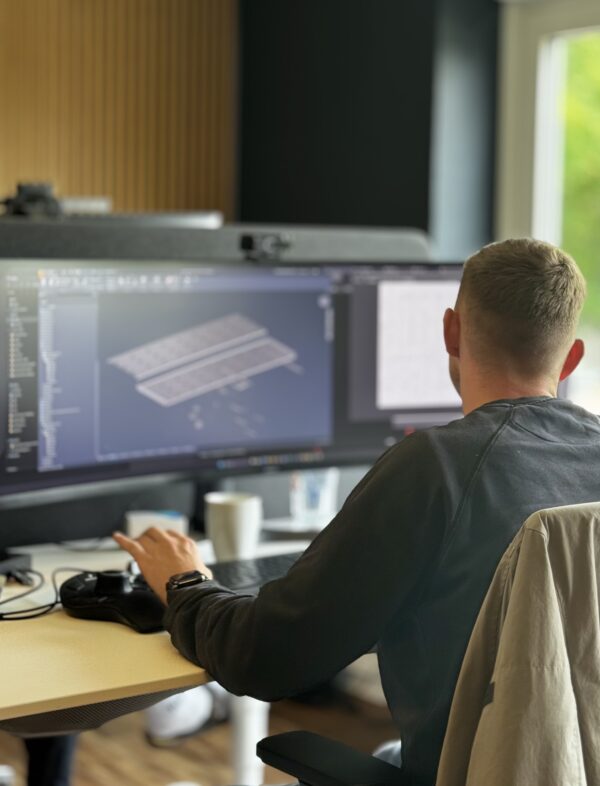 Ein Konstrukteur arbeitet konzentriert an einem CAD-Modell auf zwei Bildschirmen in einem modernen Büro – Fokus auf 3D-Konstruktion und technische Entwicklung.